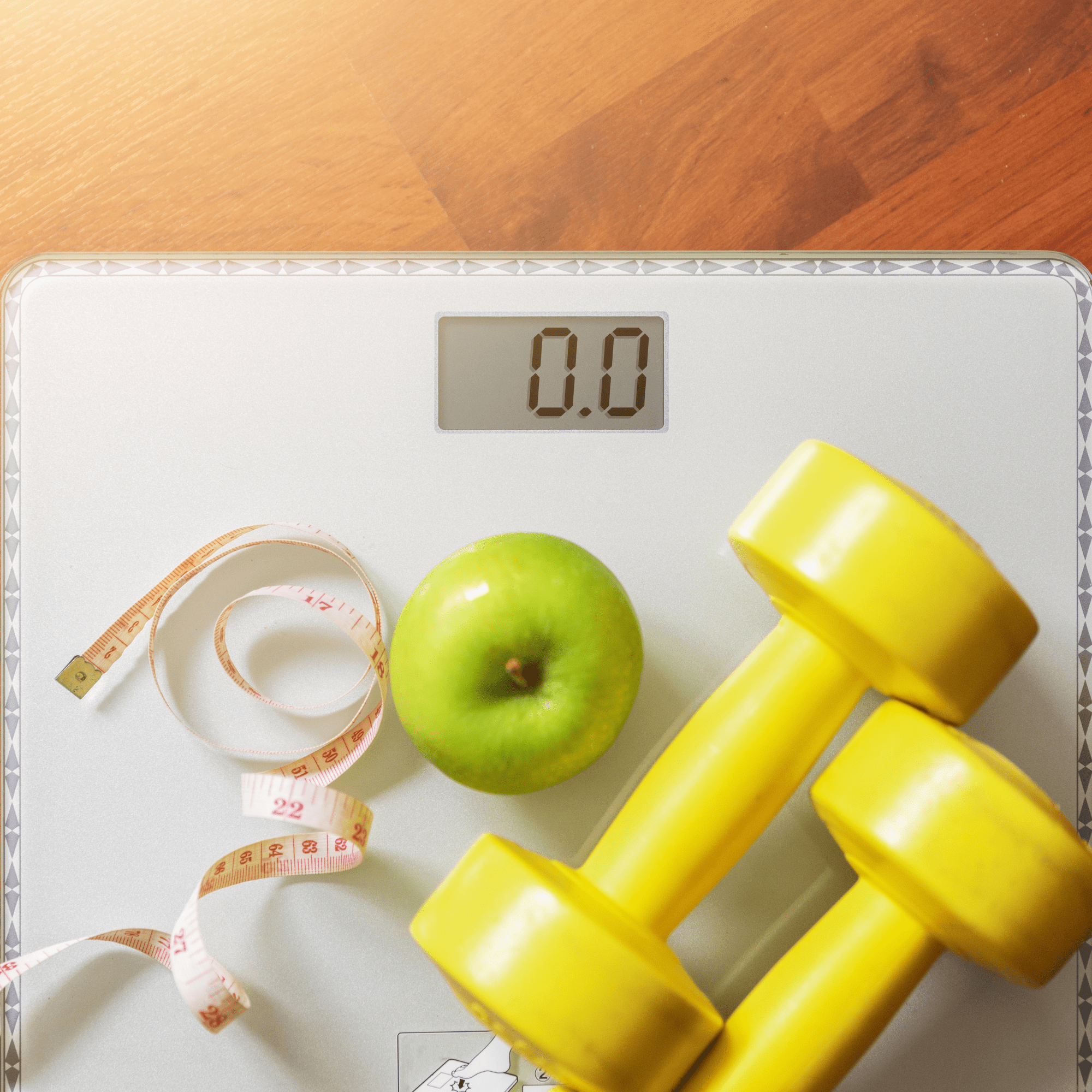 Image of scales with an apple, measuring tape and weights.